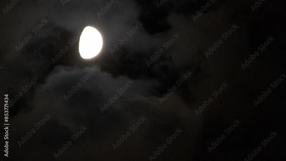 Wall mural the moon and clouds move at night.a half moon shines through a gap in the clouds covering the night 
