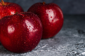 Wet and juicy fresh red apples with water drops on dark background with copy space. Selective focus