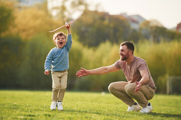 Weekend activities. Playing with toy plane. Happy father with son are having fun on the field at summertime