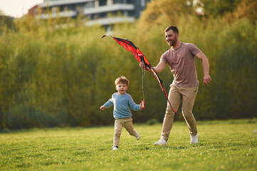 Red kite. Happy father with son are having fun on the field at summertime