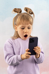 Shocked junior schoolgirl stares at phone screen gaping mouth