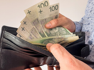  man takes Polish zlotys from his wallet. Man counting money pln