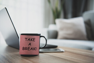 Take a break is written on a post-it and stuck on a coffee mug on my desk. It's a reminder that it's time to take a break from work.