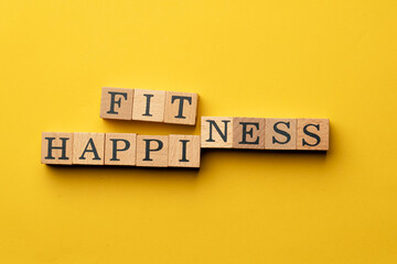 a yellow warm background without shadows wooden cubes with black letters laid out word fitness happiness
