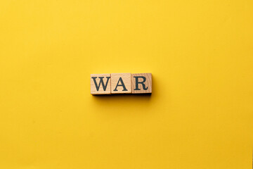 a yellow warm background without shadows wooden cubes with black letters laid out word war