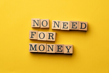 a yellow warm background without shadows wooden cubes with black letters laid out word no need for money