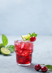 Cherry-lime mojito cocktail with mint, lime and ice on a blue background with fresh berries.