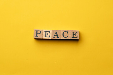 a yellow warm background without shadows wooden cubes with black letters laid out word peace