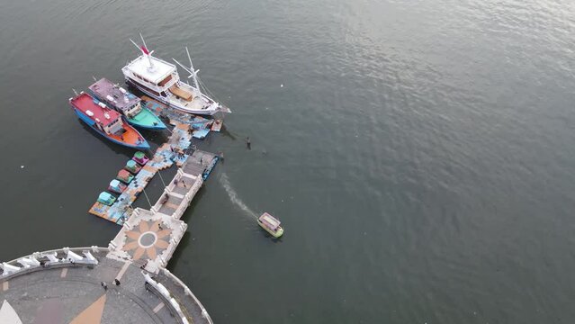 Tourist boats pass by Losari Beach, Makassar, Indonesia. While some other boats are parked at the jetty. Losari Beach is a famous beach in Makassar, one of the favorite locations.