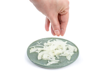 woman hand sprinkeling fine salt over chopped onion, soft focus close up