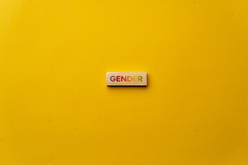a yellow warm background without shadows wooden cubes with colored letters laid out word gender