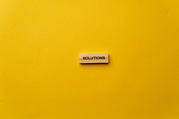 a yellow warm background without shadows wooden cubes with black letters laid out word solutions