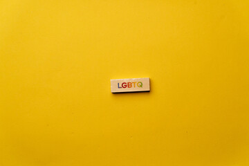 a yellow warm background without shadows wooden cubes with colored letters laid out word LGBTQ