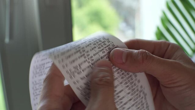 The customer checks the prices in a paper receipt from the grocery store. Calculates how much prices have increased. The concept of inflation