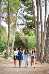 Fototapeta premium Four women are walking in a forest, enjoying each other's company