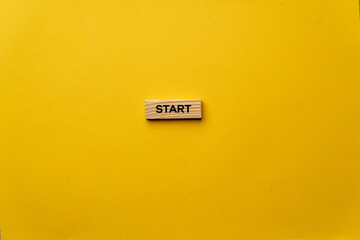 a yellow warm background without shadows wooden cubes with black letters laid out word start
