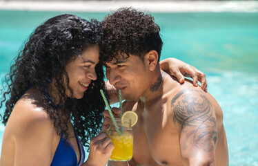 Latin couple in love enjoying time together in summer holidays drinking a refreshing cocktail