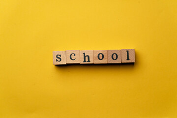 a yellow warm background without shadows wooden cubes with black letters laid out word school