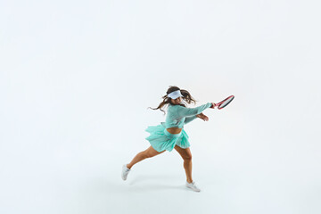 Athletic female tennis player in mint-green outfit performs forehand swing against white studio...