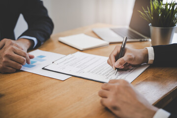 businessman sitting at desk holds pen signing contract paper, lease mortgage, employment hr or affirm partnership