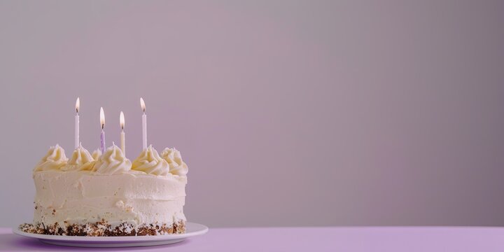 A birthday cake with lit candles on a plain background.