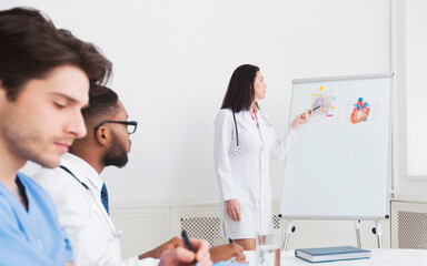 Medical lecture. Cardiologist telling theory to interns using whiteboard with pictures