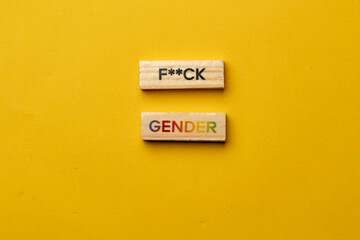 a yellow warm background without shadows wooden cubes with black letters laid out word fuck gender
