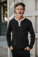 Fototapeta premium Smiling man in a dark shirt and jeans walking with hands in pockets down a city street, exuding confidence and style.