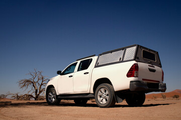 Fototapeta premium White off road car in the middle of desert on a hot sunny day