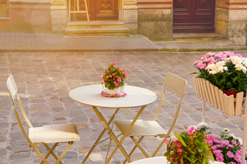 Outdoor cafe in the old town in summer. Table, chairs and flowers outside. Street cafe