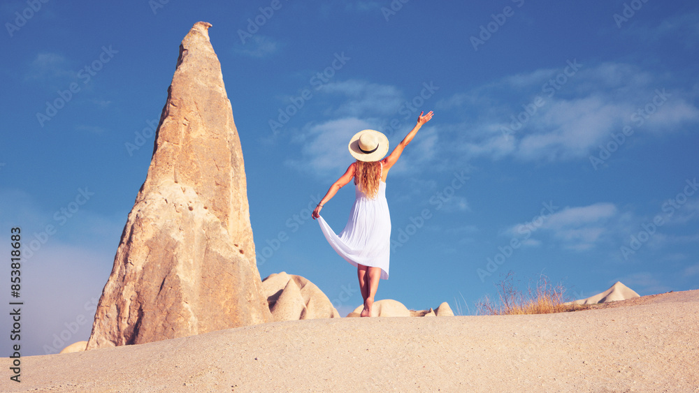 Wall mural Tourist female with white dress and summer hat enjoying panoramic view of Cappadocia landscape with rock formation