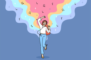 Teenage woman listens to music on headphones and dances rhythmically with hands, and uses phone with wired headset. Energetic girl with music player enjoys latest album of favorite rock band
