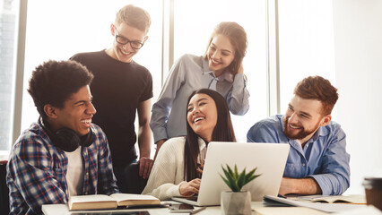 Education concept. Positive students laughing, using laptop and preparing for exams