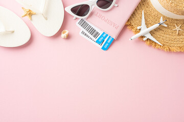 Flat lay of summer travel essentials including flip-flops, sunglasses, passport, and hat on a pink background