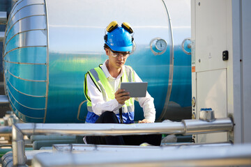 Technician working on tablet and checking pipeline valves or water tank area at urban industrial...