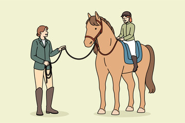 Little girl learns to ride horse and be jockey or rider, under supervision of female trainer. Riding lesson for happy child and building confidence or maintaining balance for future jockey