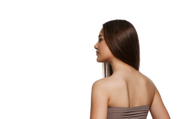 Fototapeta premium Back view image of beautiful young girl with perfect brown shiny hair and perfect well-kept skin isolated on white background. Concept of natural beauty, hair care, cosmetic products ads