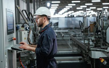 Busy employee. Factory worker is indoors with hard hat
