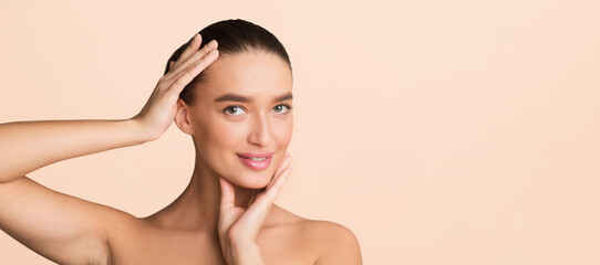Obraz premium A woman stands with her hands pressed against her cheeks, adding a dramatic effect to her pose. She looks directly at the camera, showcasing a sense of contemplation or surprise. copy space