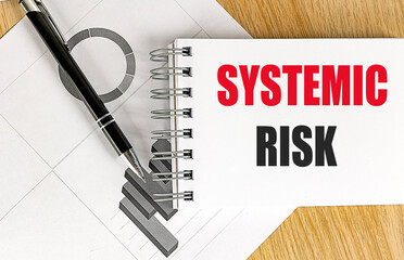 SYSTEMIC RISK text on notebook with chart on wooden background