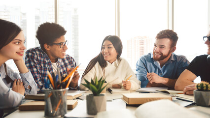 Education concept. Happy classmates having break in college library, chatting and laughing