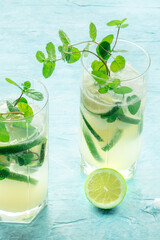 Mojito cocktails. Summer cold drinks with lime, fresh mint, and ice. Cool beverage on a blue background