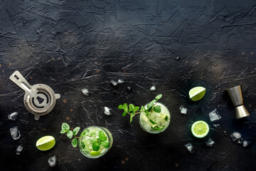 Mojito cocktail. Summer cold drink with lime, fresh mint, and ice. Cool beverage on a black background, shot from the top with copy space