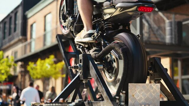 Closely examining a motorcycle on stand in an urban setting, observing in slow motion from the rear view