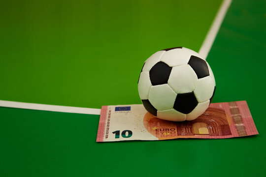 Footer ball and 10 euro bill on a green background gkak on a corner kick, close-up, sports prediction, bookmaker betting, betting on sports, betting on money game