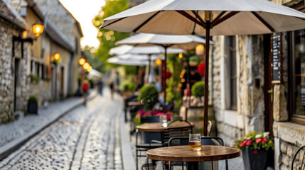 Obraz premium A street with tables and umbrellas, and a glass of beer on one of them