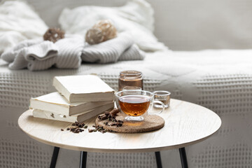 Home composition with a cup of tea, books and candles in the room.