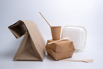 Kraft paper tableware: cups, food boxes, isolated on a light background. A set of various disposable tableware. Recycling and zero waste concept. Mock up