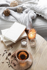 Still life with a cup of tea, books and a candle in a candlestick.
