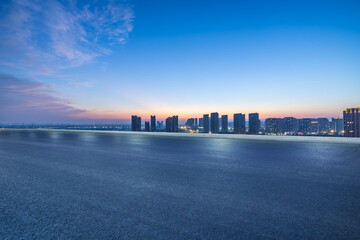 Fototapeta premium Asphalt road and city buildings with sky clouds scenery at night